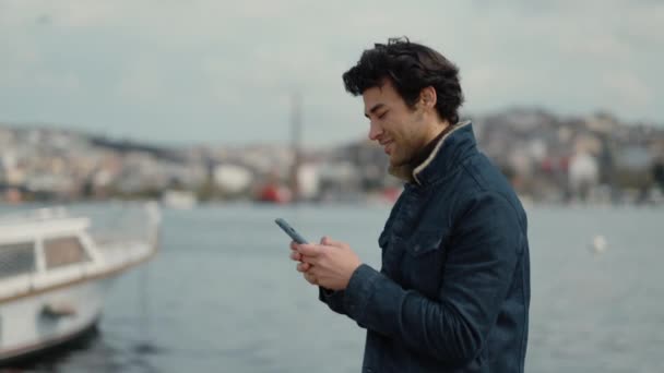Аравійський чоловік друкує повідомлення на смартфоні під час прогулянки. — стокове відео