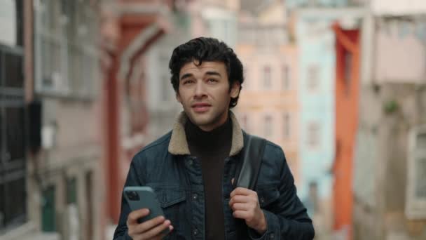 Tipo árabe caminando por la calle con mochila y teléfono inteligente — Vídeo de stock