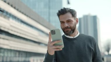 Sokakta yürüyen ve akıllı telefon kullanan pozitif iş adamı