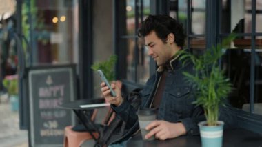 Kafede elinde kahve ve cep telefonu olan Arap bir adam dinleniyor.