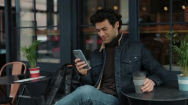 Kafe terasında otururken cep telefonu kullanan Arap turist