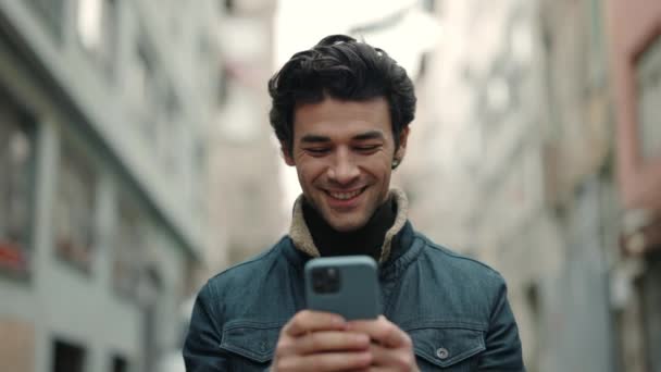 Árabe chico de pie en la calle y mensajes de texto en el teléfono inteligente — Vídeo de stock