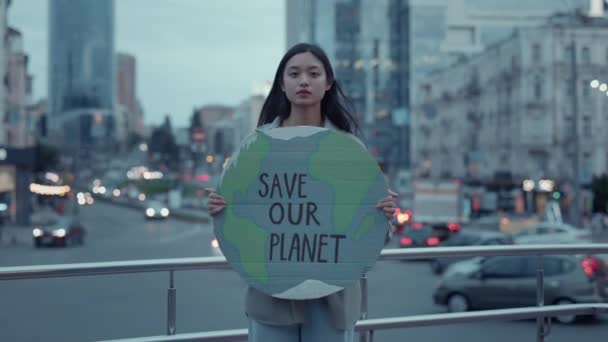 Asiatin hält Pappe mit dem Slogan "Rettet unseren Planeten" in der Hand — Stockvideo