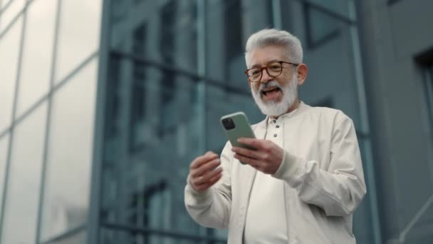 Senior man met smartphone het gevoel geluk buiten — Stockvideo