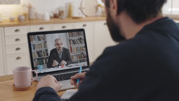 Nuori mies käyttää kannettavaa tietokonetta opetusvideoneuvotteluun — kuvapankkivideo