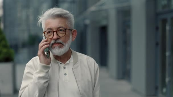 Ηλικιωμένος άνθρωπος περπατώντας στο δρόμο της πόλης και μιλώντας στο κινητό — Αρχείο Βίντεο