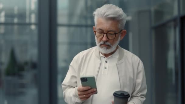 Serious aged businessman using mobile on city street — Stock Video