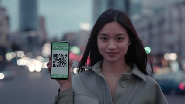 Азиатка держит мобильный телефон с паспортом здоровья на экране — стоковое видео