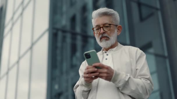 Udany starszy biznesmen korzystający z telefonu komórkowego na ulicy — Wideo stockowe