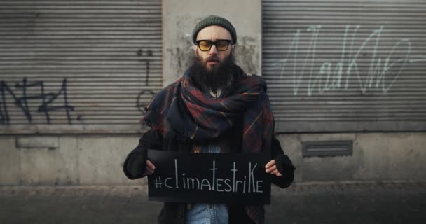 Львов, Украина - 27 ноября 2019 года: Студент мужского пола, стоящий на городской улице и держащий табличку с климатической забастовкой на ней. Хипстеры протестуют против загрязнения Земли. — стоковое видео