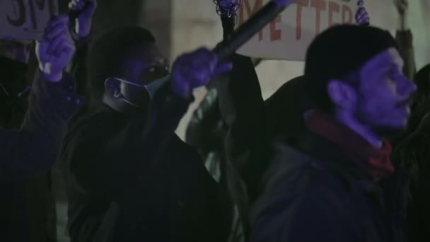 우크라이나, 리비우: 2020 년 6 월 3 일: 마스크를 쓴 사람들 플래카드를 들고 밤 거리에 서 있는 구호를 외치는 미국 국기를 들고 있다. 경찰의 만행 과 인종 차별에 대한 시위. 파업에 대한 개념. — 비디오