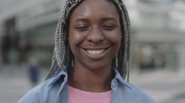 Sokakta gülümseyen rastalı Afrikalı Amerikalı kadın.
