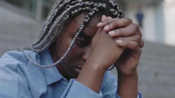 Занепокоєна афроамериканка сидить сама на вулиці. — стокове відео