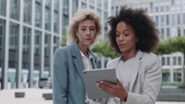 Sokaktaki iş konuşmaları sırasında tablet kullanan çeşitli kadınlar