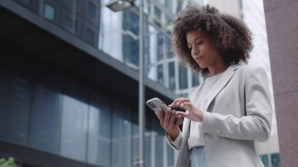 Afro-Amerikaanse vrouw in pak met behulp van mobiele op straat — Stockvideo