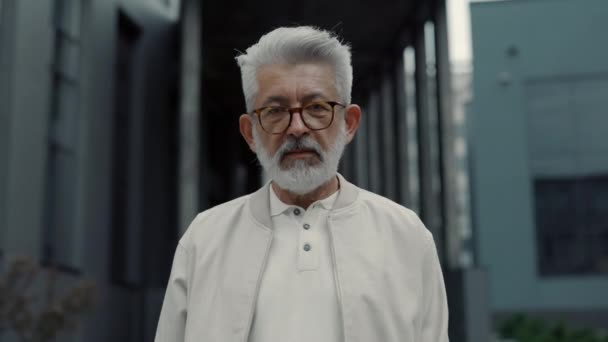 Portret van een knappe oude man in een trendy bril, kijkend naar een camera in de buurt van het kantoor. Begrip mensen, bedrijfsleven en succes. — Stockvideo