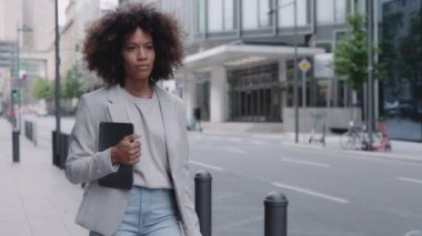 Sokakta yürüyen ve tablet taşıyan Afrikalı Amerikalı kadın.