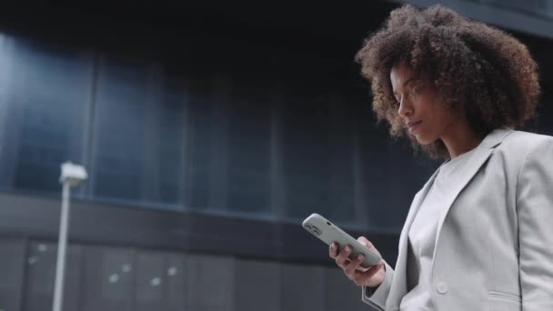 Takım elbiseli Afrikalı Amerikalı kadın sokakta cep telefonu kullanıyor. — Stok video