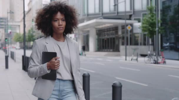 Sokakta yürüyen ve tablet taşıyan Afrikalı Amerikalı kadın. — Stok video