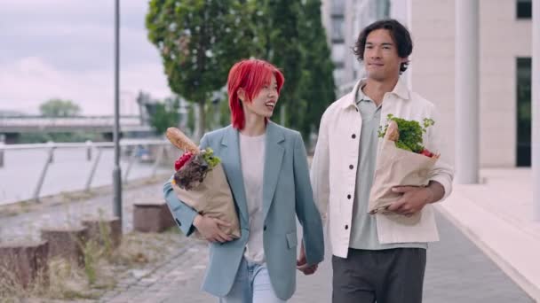 Ασιατικό ζευγάρι κουβαλάει τσάντες παντοπωλείου ενώ περπατάει στο δρόμο — Αρχείο Βίντεο