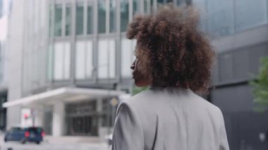 Sokakta resmi giysiler içinde yürüyen Afrikalı Amerikalı kadın.