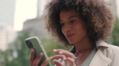 Sokakta duran ve cep telefonu kullanan Afrikalı Amerikalı kadın.