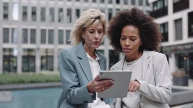 Açık havada tablet kullanan çok ırklı iş kadınları