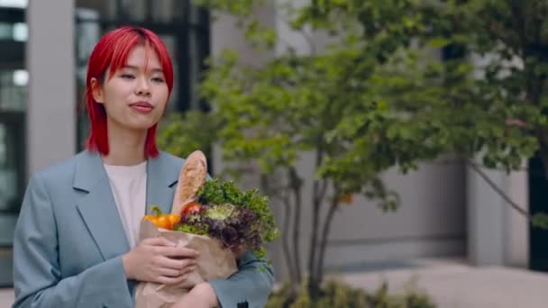 Asiatisk kvinna går på gatan och bär matsäck — Stockvideo