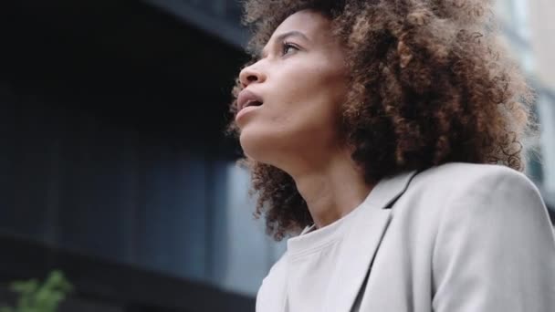 Mujer de negocios afroamericana estresada sentada al aire libre — Vídeo de stock