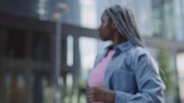 Afro-Amerikalı kadın şehir sokaklarında kameraya bakıyor.