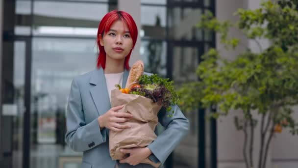 Asiatisk kvinna med matsäck i händerna går på gatan — Stockvideo