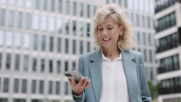 Business woman reading good news on mobile outdoors — Stock Video
