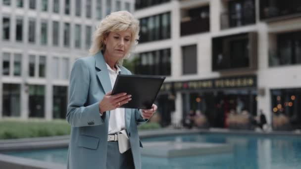 Mujer de negocios mirando a través de documentos mientras camina — Vídeos de Stock