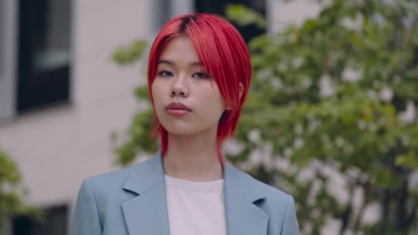 Mujer de negocios asiática con el pelo rojo posando en la calle de la ciudad — Vídeos de Stock