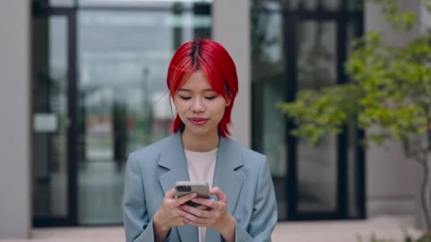 Asiatin läuft auf Straße und benutzt Smartphone — Stockvideo