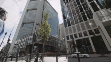 Frankfurt, Almanya, Ağustos 2021: Büyük şehrin caddesinde yürüyen Afrika kökenli Amerikalı kadın. Mavi gömlekli ve siyah pantolonlu genç bayan. Çevredeki modern gökdelenler.