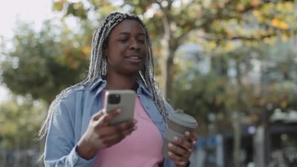 Женщина с кофе и мобильным выходом на улицу — стоковое видео