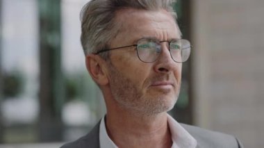 Açık havada kameraya bakan başarılı bir olgun adam.