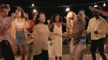 Dans eden ve çatıya konfeti atan çok kültürlü arkadaşlar.