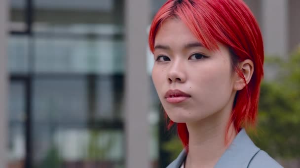Selbstbewusste Asiatin mit roten Haaren steht im Stadtgebiet — Stockvideo