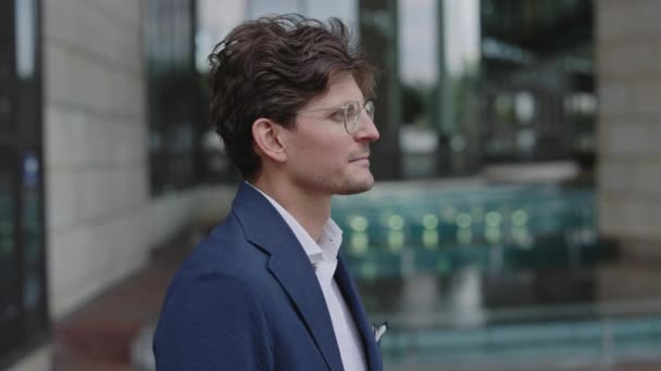 Üzletember szemüvegben és öltönyben pózol a szabadban — Stock videók