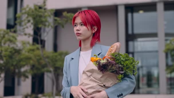 Asiatisk kvinna som håller matsäck stående utomhus — Stockvideo