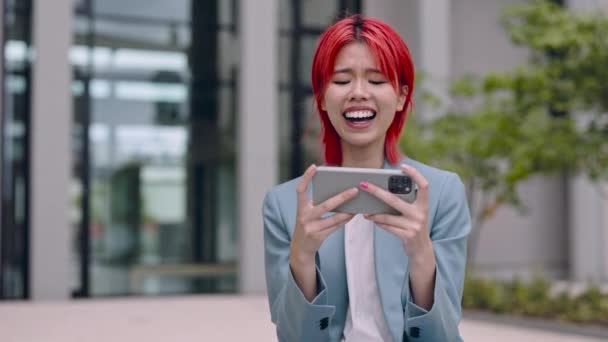 Asiatin lächelt fröhlich, während sie auf Handy schaut — Stockvideo