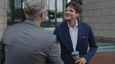 Resmi kıyafetler içinde iş arkadaşları sokakta konuşuyor.