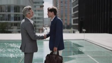 İki iş ortağı dışarıda el sıkışıyor.