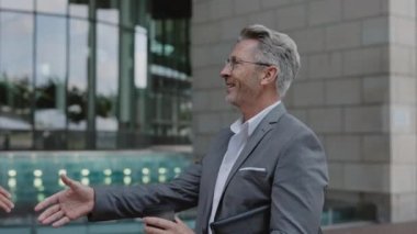 Şehir caddesinde dikilen iki işadamı el sıkışıyor