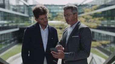İş arkadaşları şehir caddesinde akıllı telefon kullanıyor