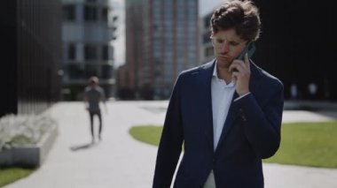 Takım elbiseli adam dışarıda gezici konuşma yapıyor.