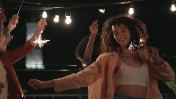 Gente multiétnica bailando en el techo con bengalas en las manos — Vídeo de stock