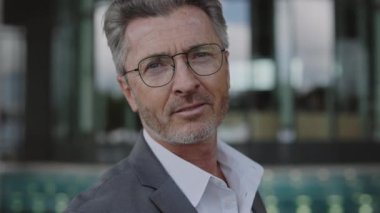 Kentsel alanda resmi giyinmiş yaşlı bir işadamı duruyor